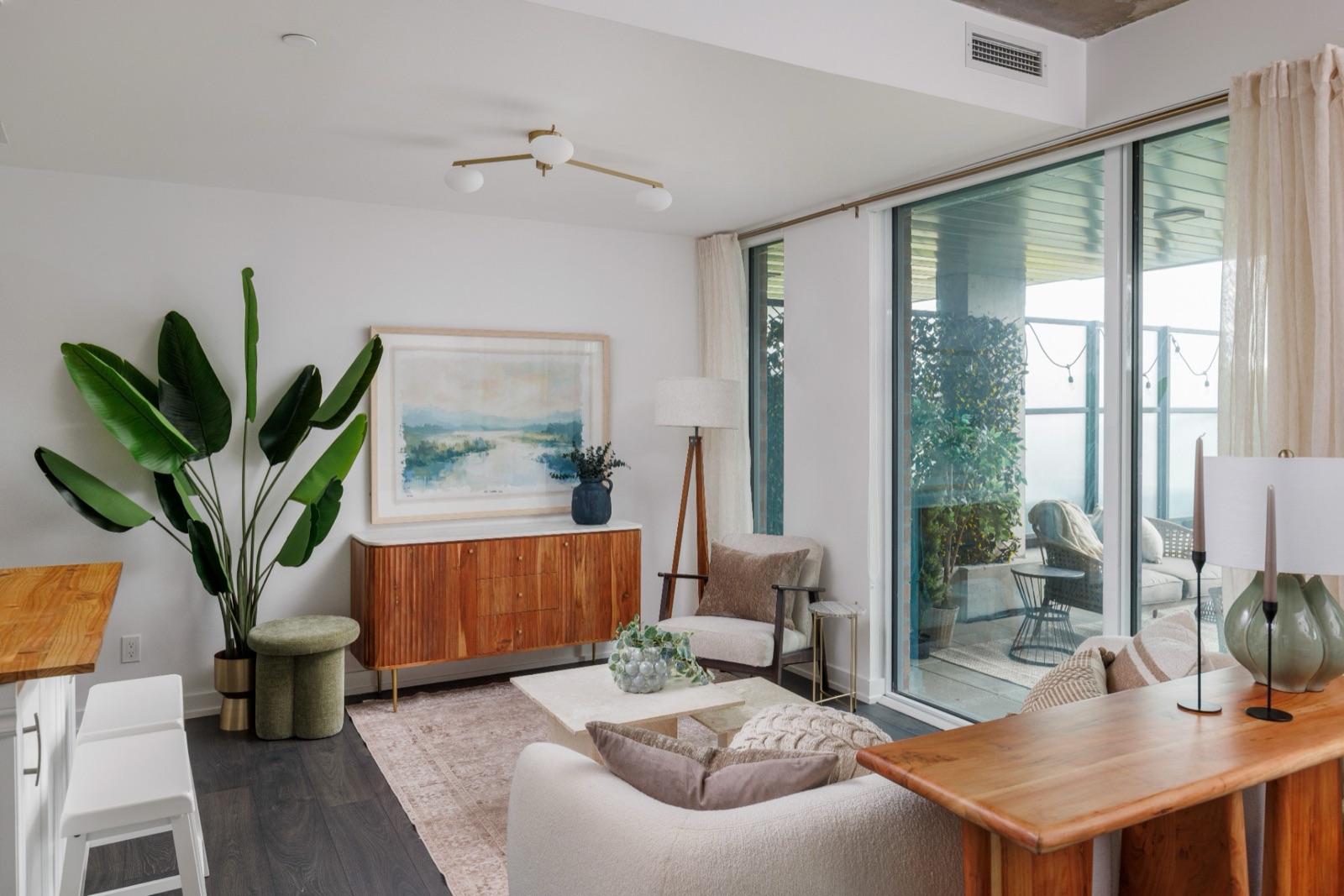 Living room with a curved sofa, walnut sideboard and the terrace beyond
